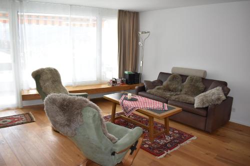 a living room with two chairs and a couch at Haus im Park 11 in Valbella