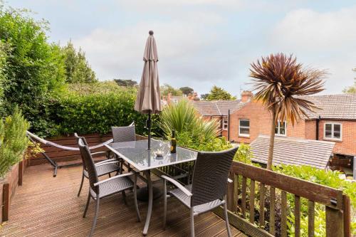 a patio with a table and chairs and an umbrella at Host & Stay - Clearmount Cottage in Weymouth