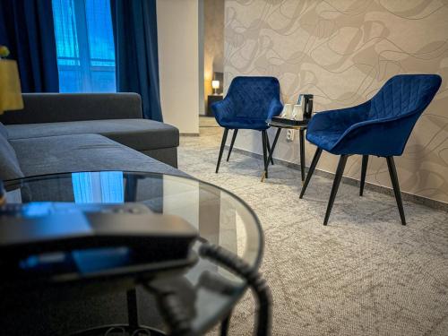 a living room with two blue chairs and a glass table at Hotel Modena in Bratislava