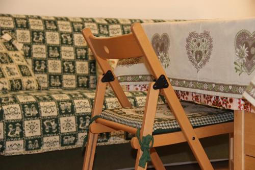 a wooden chair with a quilt on it next to a couch at Residence Fontanazzo in Campitello