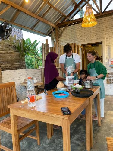 a group of people standing around a wooden table at Stay Together in Tetebatu