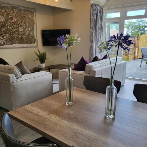 two vases with flowers on a wooden table in a living room at Arkle in Kelling