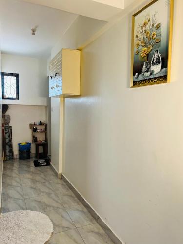a room with a white wall and a painting on the wall at Tranquil space with aerial Mombasa view in VOK off nyali road in Kisauni