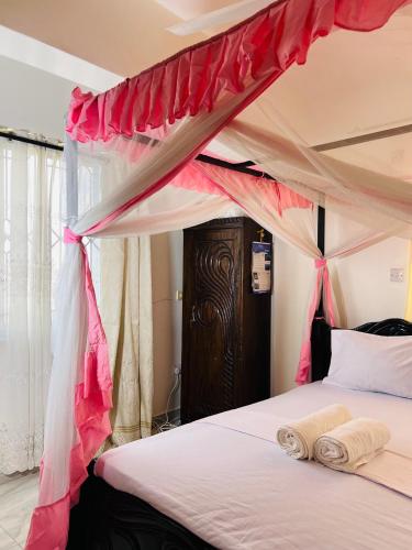 a bedroom with a canopy bed with two towels on it at Tranquil space with aerial Mombasa view in VOK off nyali road in Kisauni