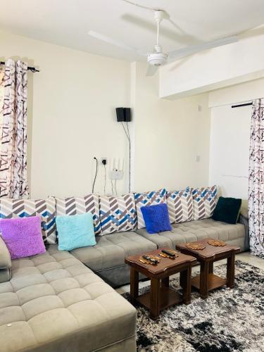 a living room with a couch with colorful pillows at Tranquil space with aerial Mombasa view in VOK off nyali road in Kisauni