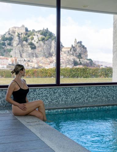 a woman is sitting next to a swimming pool at Domus Hotel in Bagnoli del Trigno