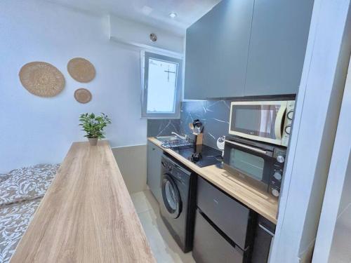 une petite cuisine avec un micro-ondes et une cuisinière dans l'établissement Studio cosy proche plage, parking gratuit, à Juan-les-Pins