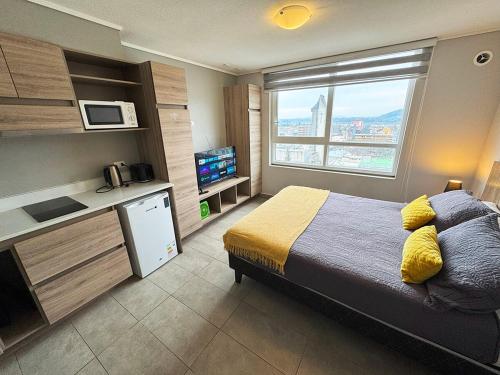 ein Schlafzimmer mit Bett und eine Küche mit Fenster in der Unterkunft Apart Hotel Bauerle & Apartamentos in Temuco