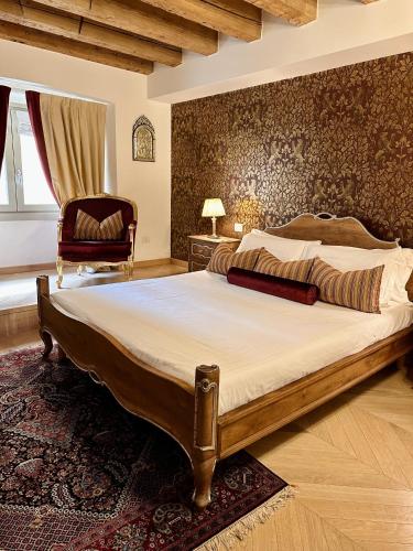 une chambre avec un grand lit et une chaise dans l'établissement The Ambassador Apartment by Palazzo Monga, à Vérone