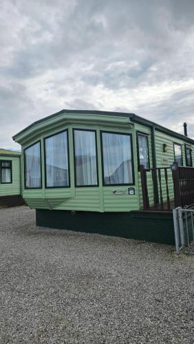 a green mobile home sitting on top of gravel at The Lake District Caravan in Lamplugh
