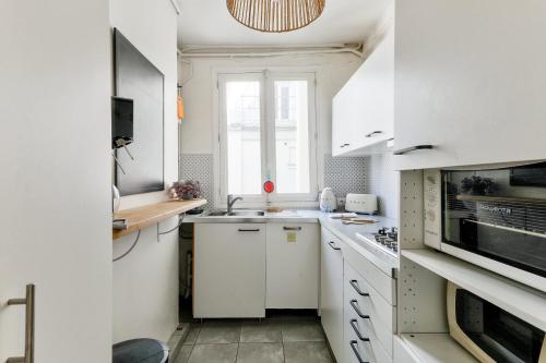 une cuisine blanche avec un évier et un micro-ondes dans l'établissement GuestReady - Séjour paisible à Paris, à Paris