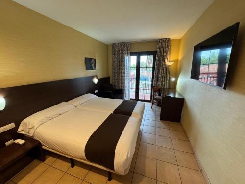 a hotel room with a bed and a window at Hotel Canal Olímpic in Castelldefels
