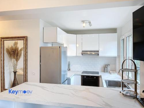 a kitchen with white cabinets and a stainless steel refrigerator at 2 pièces lumineux proche Paris - Parking gratuit in Fresnes