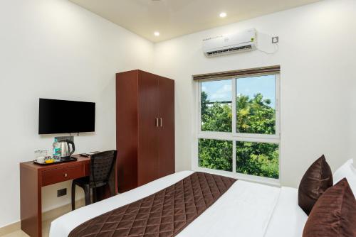 a bedroom with a bed and a desk and a window at The Lotaz Hotel in Cochin