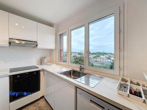 a kitchen with a sink and a large window at 2 pièces lumineux proche Paris - Parking gratuit in Fresnes