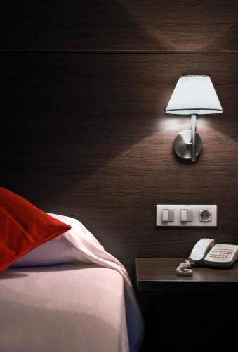 a bedroom with a bed with a lamp and a phone at Hotel Canal Olímpic in Castelldefels