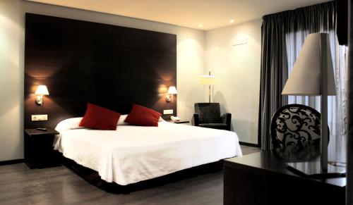 a hotel room with a large bed and a chair at Hotel Canal Olímpic in Castelldefels