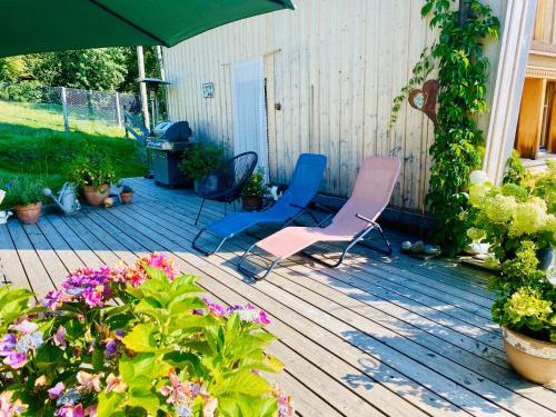 two chairs and an umbrella on a deck with flowers at Birkenhof, Haus Märli in Herisau