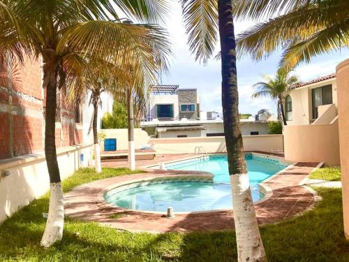 a swimming pool between two palm trees in a yard at Depto a 3 cuadras de la playa in Boca del Río