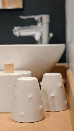 two white cups sitting on a wooden counter with a sink at Le Clos Du Perret in Chaussan