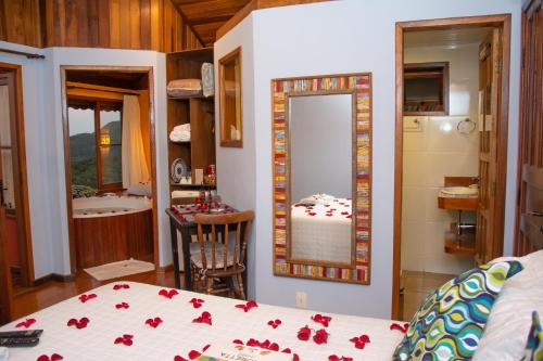 a bedroom with a bed and a mirror and a bathroom at Pousada Portal Dos Ventos in Visconde De Maua