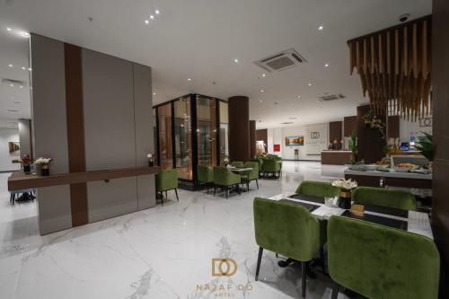a lobby with a table and green chairs at Najaf Do Hotel in An Najaf