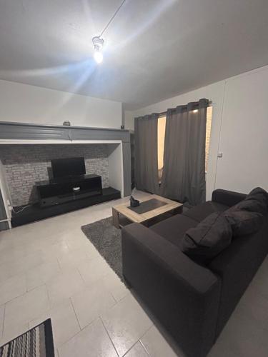 - un salon avec un canapé noir et une cheminée dans l'établissement Appartement rez-de-chaussée, centre-ville, à Briatexte