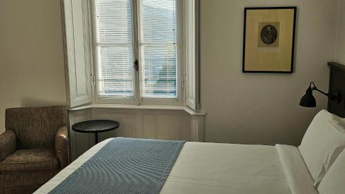 a bedroom with a bed and a chair and a window at Casa Santo Stefano in Cernobbio