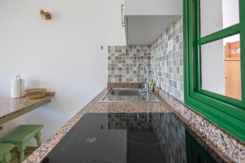 una cocina con fregadero y una ventana verde en Private Solarium Bungalow Garden, en Maspalomas