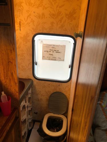 a small bathroom with a toilet and a window at VINTAGE CARAVANE in Les Attaques