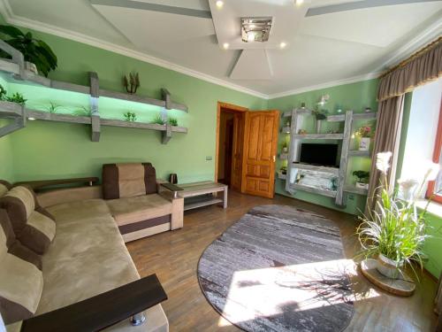 a living room with green walls and a couch at Cottage Kazka Lisu in Skhidnitsa