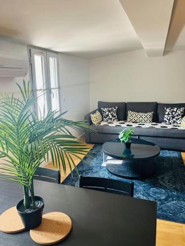 un salon avec un canapé et une table avec une plante dans l'établissement Somptueux T3 neuf centre ville, à Sète