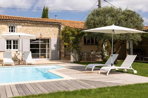 a pool with two chairs and an umbrella at La bastide de Margaux in Soussans
