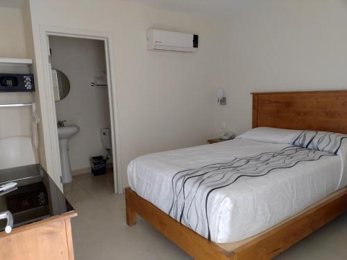 a bedroom with a bed and a bathroom with a television at Hotel Baja in Tijuana