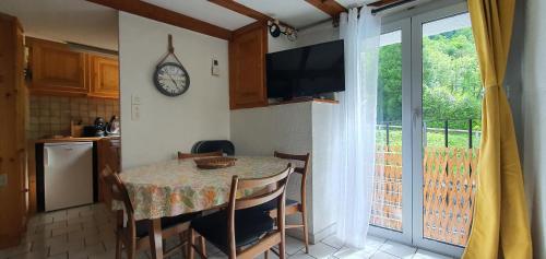 une cuisine avec une table, des chaises et une horloge murale dans l'établissement Le Georgina Cauterets, à Cauterets