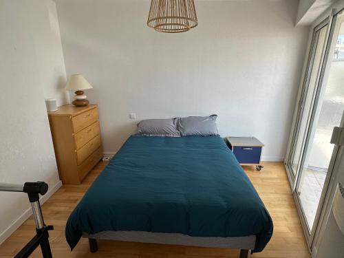 une chambre avec un lit avec une couverture bleue dans l'établissement Appartement Face Mer Saint Nazaire, à Saint-Nazaire