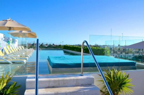 una piscina con sedie e un ombrellone di Anah Playa Luxury Penthouses and Apartments a Playa del Carmen