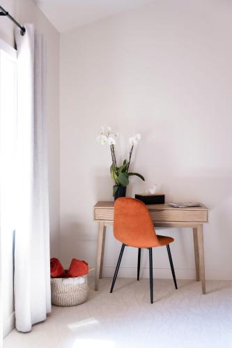 a desk with a chair and a vase with flowers at La Bastide de Montferrat in Montferrat
