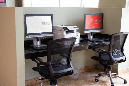 two computers sitting on a desk with two chairs at Hilton Garden Inn Lima Surco in Lima