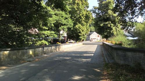 an empty road with a stone wall and a house at Carpe Diem in Resteigne