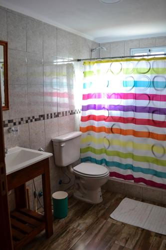 a bathroom with a toilet and a colorful shower curtain at Postal del Ceferino in Sierra de la Ventana