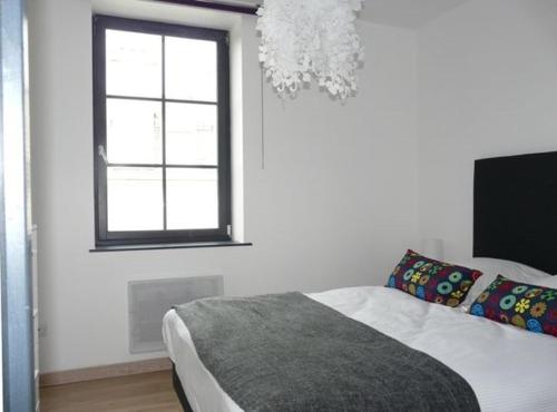 a bedroom with a bed and a window and a chandelier at Les Mini-lofts de Paul et Virginie in Wimereux