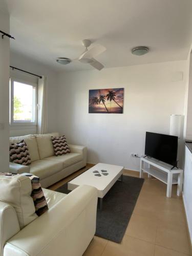 a living room with a couch and a tv at Condado de Alhama, Jardin 7 in Alhama de Murcia