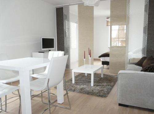una sala de estar blanca con mesa blanca y sillas en Les Mini-lofts de Paul et Virginie, en Wimereux