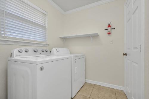 a white laundry room with a washing machine and a window at Family Fun Oasis Pool Hot Tub and Play Area in Houston