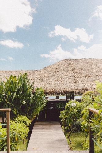a straw hut with a wooden walkway and some plants at Kabana Hotel in Prea