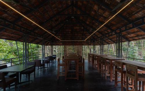 a restaurant with tables and chairs in a forest at Lakedale Resorts in Thekkumkara