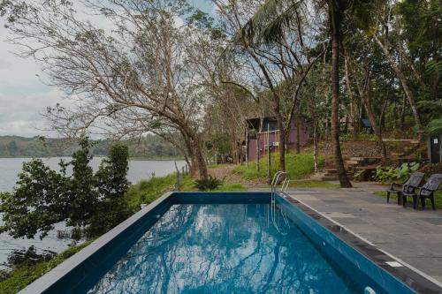 a swimming pool next to a body of water at Lakedale Resorts in Thekkumkara