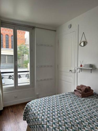 une chambre avec un lit et une grande fenêtre dans l'établissement Joli & cosy 2 pièces à Paris, à Paris