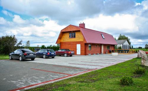 a building with cars parked in a parking lot at Poilsio namai Aerodromas in Bajorai